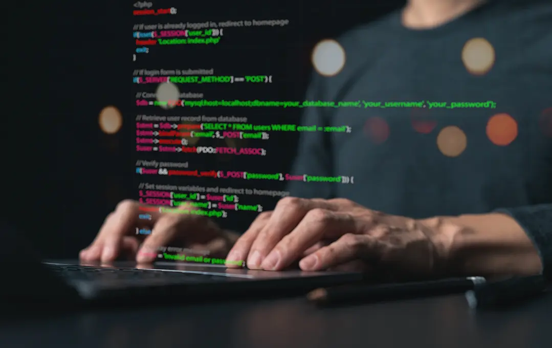 Nahaufnahme von Händen, die auf einem Laptop tippen, darüber farbiger Code.